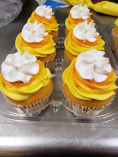 several cupcakes with white frosting and orange icing