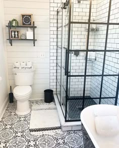 a white toilet sitting next to a bath tub in a bathroom on top of a black and white floor