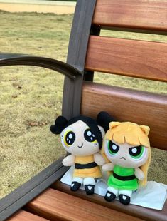 two small stuffed animals sitting on top of a wooden bench next to eachother