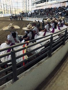 several people in mexican attire are sitting on the bleachers at a rodeo arena