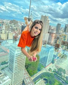 a beautiful young woman standing on top of a tall building with her arms outstretched in the air