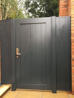 a grey gate is open on the side of a brick building