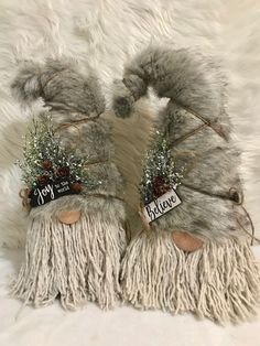 two furry gray gnomes with christmas decorations on their heads and feet, one has a name tag that says happy new year