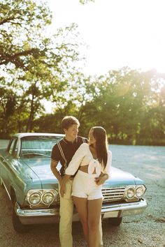 a man and woman standing next to a car