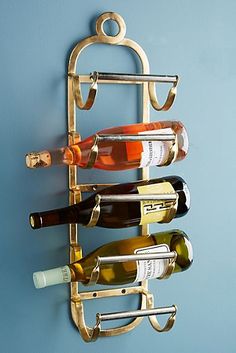 a metal wine rack holding several bottles of wine on it's side against a blue wall