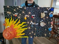 a young boy is holding up a solar system art project