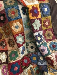 an old quilt is laying on top of a bed with many different colors and shapes