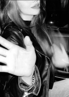 black and white photograph of woman in leather jacket holding her hand out to the side