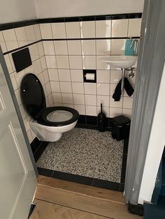 a bathroom with black and white tiles on the floor, toilet and sink in it