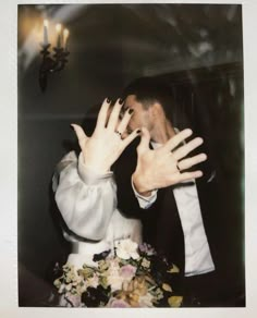 a man in a suit and tie holding his hands up to the camera while sitting at a table