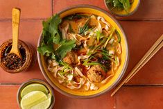 an overhead view of a bowl of noodles with meat, vegetables and sauces on the side