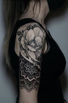 a woman with a black and white flower tattoo on her upper arm, showing the detailed details