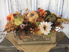 a wooden box filled with flowers and leaves on top of a piece of burlock