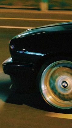 a black car driving down a street next to tall buildings