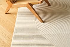 a chair sitting on top of a wooden floor next to a white rug with stripes