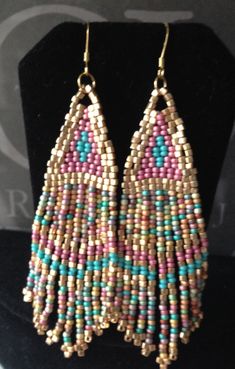 beaded earrings with pink, blue and green beads on a black display stand at a jewelry store