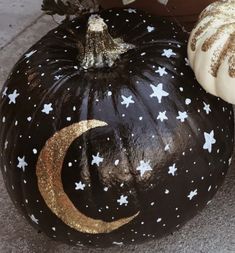 two painted pumpkins sitting next to each other on the ground with stars and moon designs