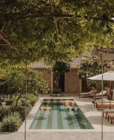 an empty pool surrounded by tables and umbrellas in the middle of a courtyard area