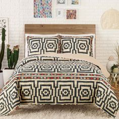 a bed with a black and white bedspread next to potted cacti