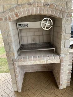 an outdoor bbq grill built into the side of a brick wall with a door open