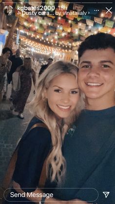 a man and woman standing next to each other in front of a string of lights