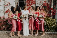 a group of women standing next to each other in front of a building with flowers