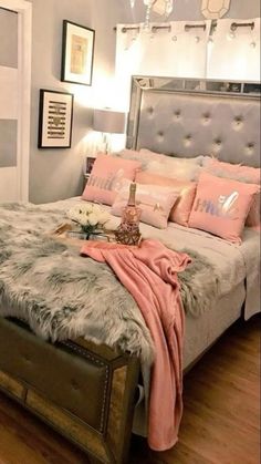 a bedroom with a large bed covered in pink and gray blankets, pillows and decor