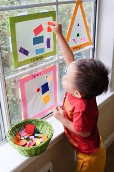 a little boy that is standing in front of a window with some magnets on it