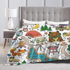 a bed covered in a white comforter with cartoon animals and camping items on it