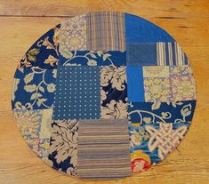 a blue patchwork plate sitting on top of a wooden table next to a wood floor