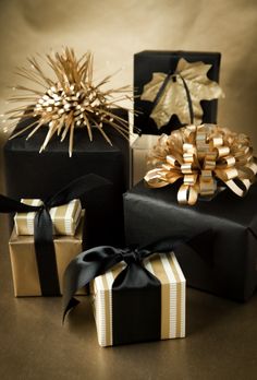 three black boxes with gold ribbons and bows