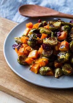 brussel sprouts and carrots on a plate with a wooden spoon