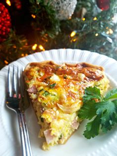 a piece of quiche on a plate with a fork and christmas tree in the background