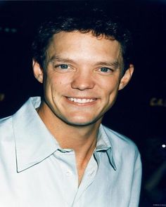 a man in a white shirt smiling at the camera