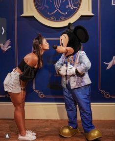 two people standing next to each other in front of mickey mouse and minnie mouse head