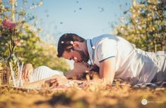 a man and woman laying on the ground in front of trees, grass and flowers