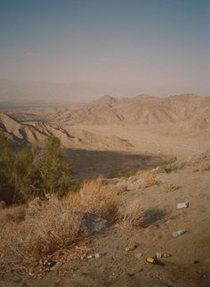 there are many bottles and trash on the ground in this desert area with mountains in the background