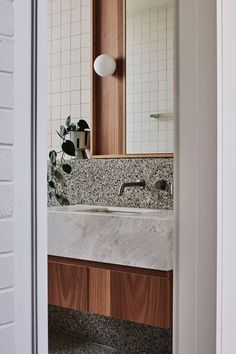 a bathroom sink sitting under a mirror next to a wooden cabinet and white tiled walls