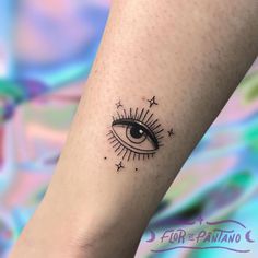 an eye tattoo on the left arm with stars and sunbursts around it