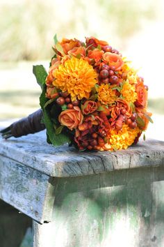 a bouquet of flowers sitting on top of a wooden bench