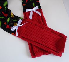 two red oven mitts with white bows on them sitting next to eachother