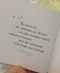 a hand holding an open book with a quote on it