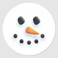 a white plate topped with an orange carrot and black beans next to a face drawn in the shape of a snowman