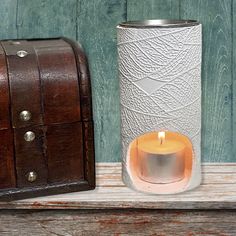 a lit candle sits next to an old trunk