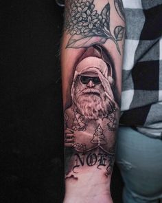 a person with a tattoo on their arm that has an image of santa claus and flowers