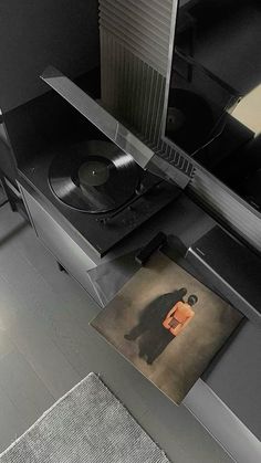 a record player sitting on top of a table next to a rug with a painting