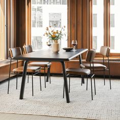 a dining table with four chairs and a vase filled with flowers on top of it