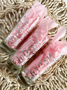 three jars filled with pink tissue paper sitting on top of a wicker tablecloth