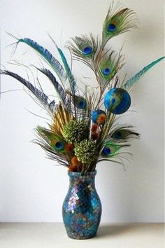 a vase filled with lots of colorful feathers on top of a white table next to a wall