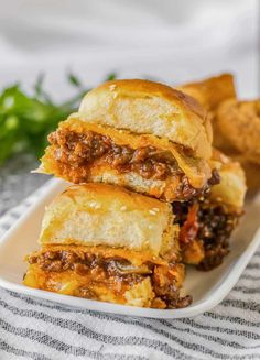 three sandwiches stacked on top of each other with meat and cheese in the middle, sitting on a white plate